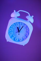 Light blue alarm clock suspended in air on a bright purple background