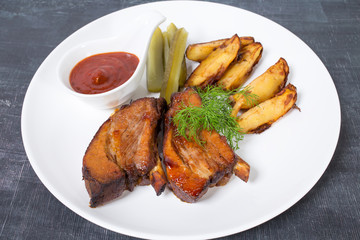 Roast pork ribs with potatoes and pickles.