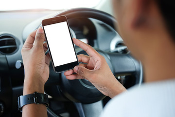 Cropped shot view The driver uses the phone while driving. Modern smart phone with round edges. Isolated screen for mockup. Car navigation display in background. 