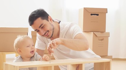 Father and son assembling furniture. Boy helping his dad at home. Happy Family concept.