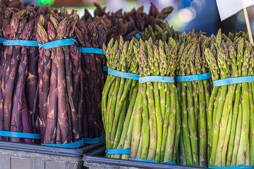 large bundles of freshly harvested asperagus from local farms in a stand in a market