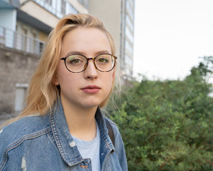 portrait of a young girl in fashionable glasses on the street in the daytime