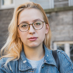 portrait of a young girl in fashionable glasses on the street in the daytime