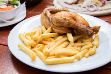 Halber Hahn Brathänchen mit Pommes auf Porzellan Teller draußen im Biergarten
