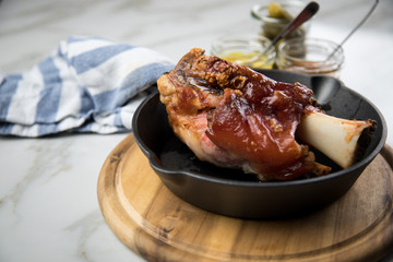 Gegrillte Schweinefleisch Haxe in gusseiserne Pfanne auf Holzbrett mit Cornichons, süßen und...