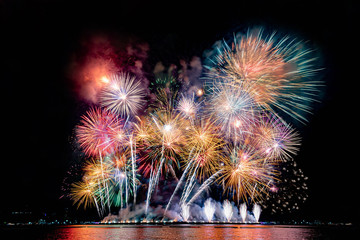 Amazing beautiful colorful fireworks display on celebration night, showing on the sea beach with multi color of reflection on water