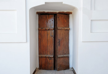 Old wooden door in the white wall.