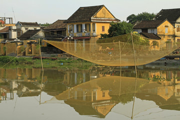 Fototapeta na wymiar Vietnam house with suspended fishing net reflected in river. ie