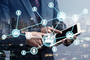 double exposure of businessman using cellphone or smart phone with organization system and city night background, network technology connection concept