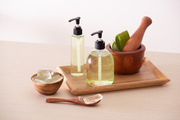 Bolw of aloe on cutting board and organic shower gel in bottle on wood tray
