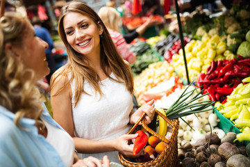 Young women friends baying vegetables and fruits on the market