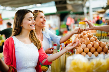 Young happy women shopping vegetables and fruits on the market