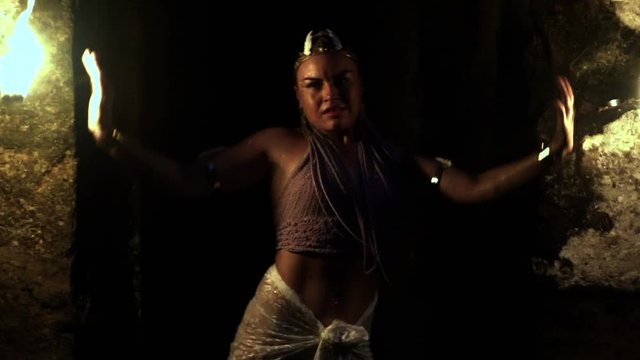 The girl in the cave dangerously conducts fire all over her body. Night timelapse in a cave.