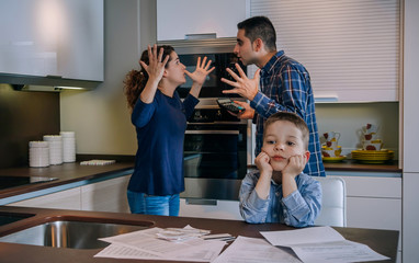Parents arguing heatedly in the kitchen with their little son in front