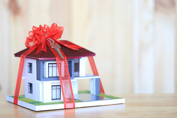 Real estate and Gift new home concept,Model house with Red ribbon and key on white background