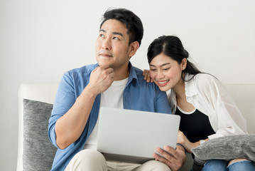 Fototapeta premium Happy Asian couple shopping online with holding credit card and laptop and sitting at home together, lifestyle concept.