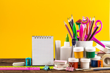 Notepad and colorful School stationery on yellow background