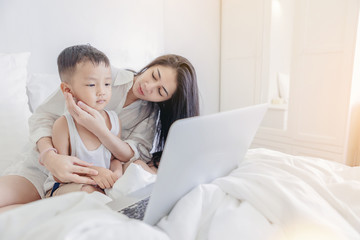 Fototapeta premium Computer addiction concept. Mother take care her boy because of overuse the laptop computer in the bed room.