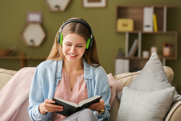 Young woman listening to music and reading book at home