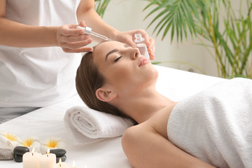 Obraz na płótnie Canvas Beautiful woman undergoing treatment with face serum in beauty salon