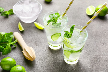 Glasses of fresh mojito, lime and juicer on table