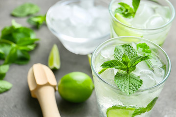 Glasses of fresh mojito, lime and juicer on table, closeup