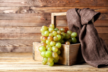 Basket with tasty sweet grapes on wooden table