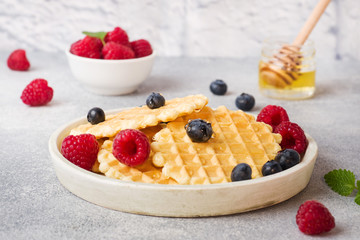 Corrugated waffle cookies with fresh raspberries and blueberries on a concrete background. Copy space.