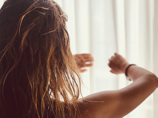 Fototapeta premium Silhouette of a girl while waking up in the room and holding curtain.
