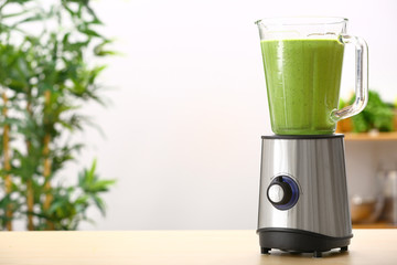 Blender with healthy smoothie on table in kitchen