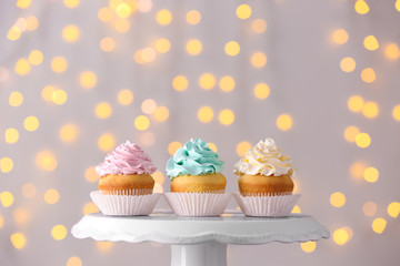Tasty Birthday cupcakes on stand against defocused lights