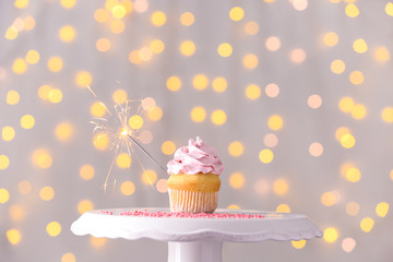 Tasty Birthday cupcake on stand against defocused lights