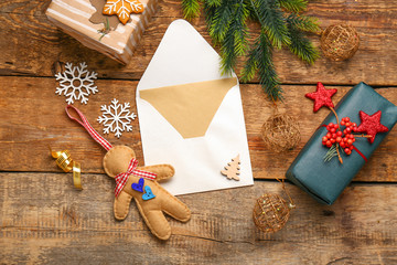 Envelope with gift boxes and Christmas decor on wooden background