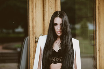 beautiful brunette woman with long hair in a white suit and lace top