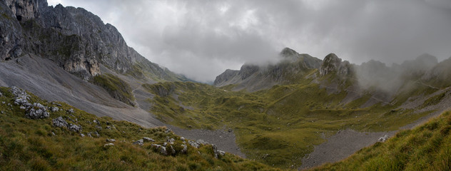 Beautiful rocky mountain landscape during  during a cloudy day. Fog and mist surrounding the green landscape