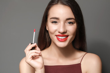 Fototapeta premium Beautiful young woman with bright lipstick on grey background