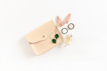 Minimalistic fashion composition with handbag, women's cosmetics and accessories on white background