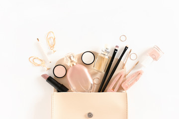 Fashion composition with women's cosmetics and accessories in handbag on white background