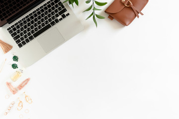 Composition on white desk with laptop, women's accessories and ruscus branch