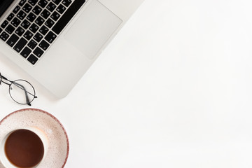 Minimalistic workspace with laptop, mug of coffee, glasses on white background