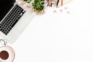 Feminine workspace with laptop, mug of coffee, flowers, stationery on white background