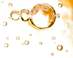 Bubbles of air on the smooth surface of golden water as an abstract background