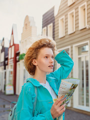 redhead young woman travel over West Europe and using paper map in unknown town. Travel photo. Lost in new city