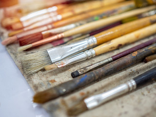 Fototapeta premium Artist paint brush set. Close-up many artist tools in calico paint brush holder.