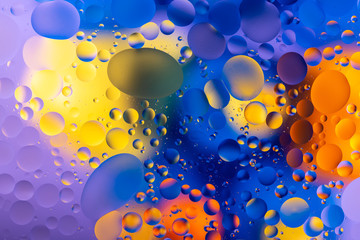 bright oily drops in water with colorful background, close-up 