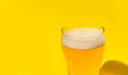 Beer. Cold Craft light Beer in a glass with water drops. Pint of Beer close up isolated on yellow color background with copy space.Oktoberfest concept.
