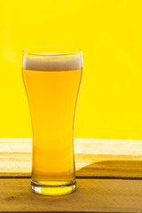 Beer. Cold Craft light Beer in a glass with water drops. Pint of Beer close up isolated on yellow color background with copy space.Oktoberfest concept.