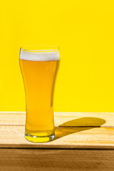 Beer. Cold Craft light Beer in a glass with water drops. Pint of Beer close up isolated on yellow color background with copy space.Oktoberfest concept.