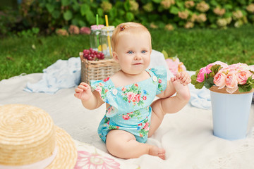 Children Protection Day, baby girl in the park sits in a basket on a summer picnic