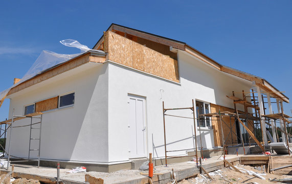 Modern house construction site with plastering walls, scaffolding exterior
